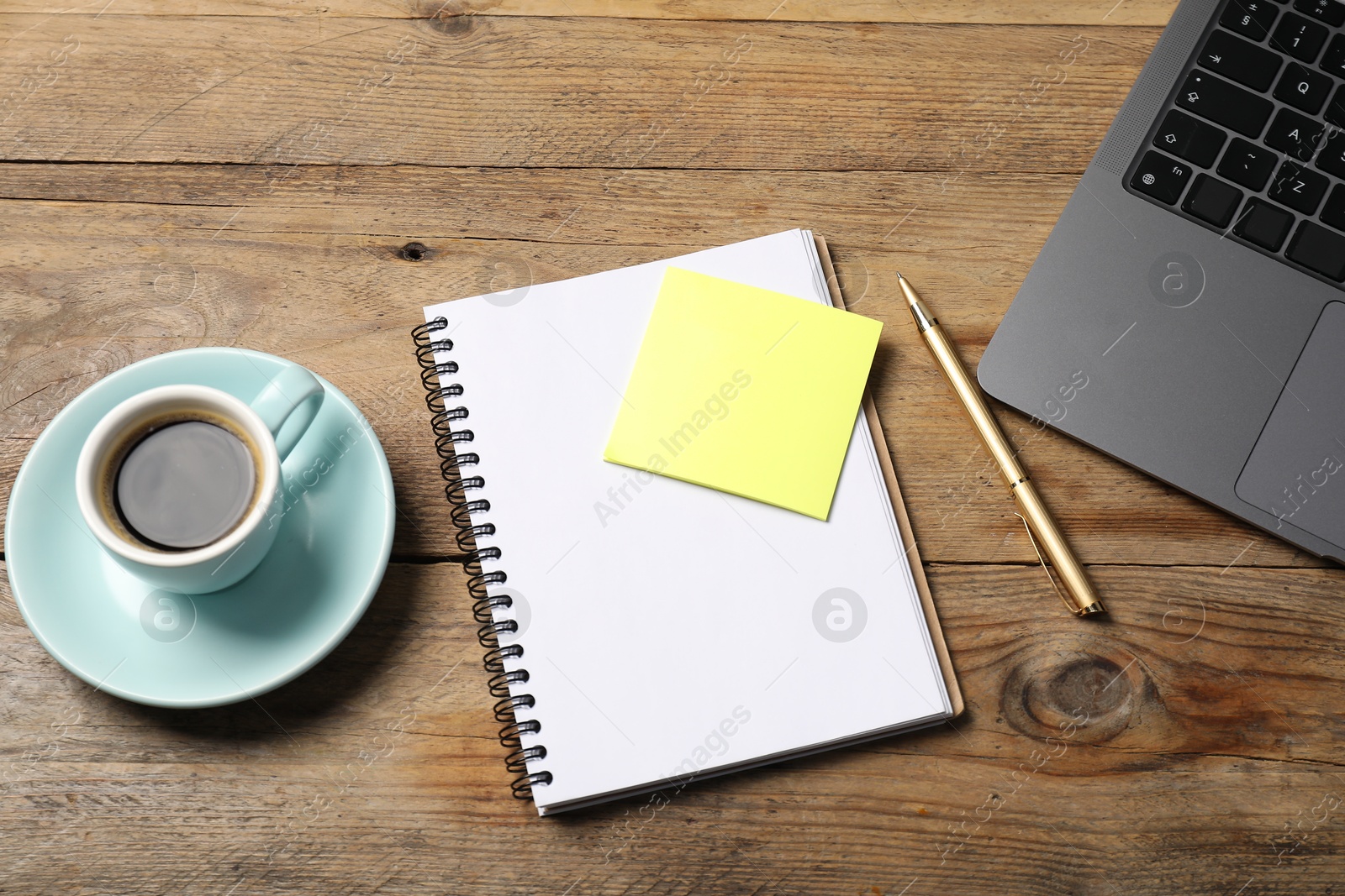 Notebook with pen, sticky note, laptop and coffee on wooden table, above view Photo of Notebook with pen, sticky note, laptop and coffee on wooden table, above view