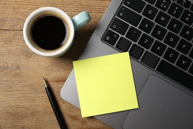Photo of Laptop with sticky note, pen and coffee on wooden table, top view