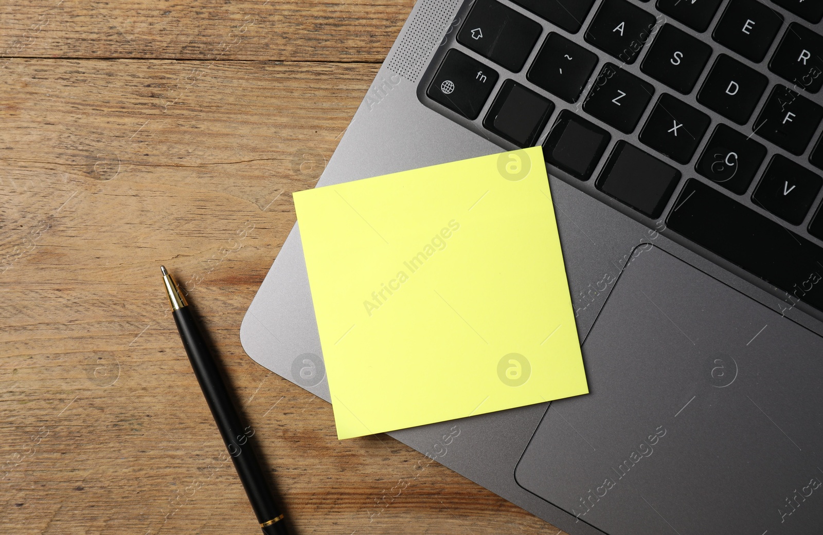 Laptop with sticky note and pen on wooden table, top view Photo of Laptop with sticky note and pen on wooden table, top view