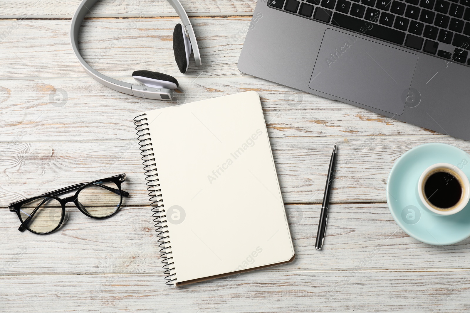 Notebook with pen, laptop, glasses, headphones and coffee on white wooden table, flat lay Photo of Notebook with pen, laptop, glasses, headphones and coffee on white wooden table, flat lay