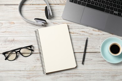 Photo of Notebook with pen, laptop, glasses, headphones and coffee on white wooden table, flat lay