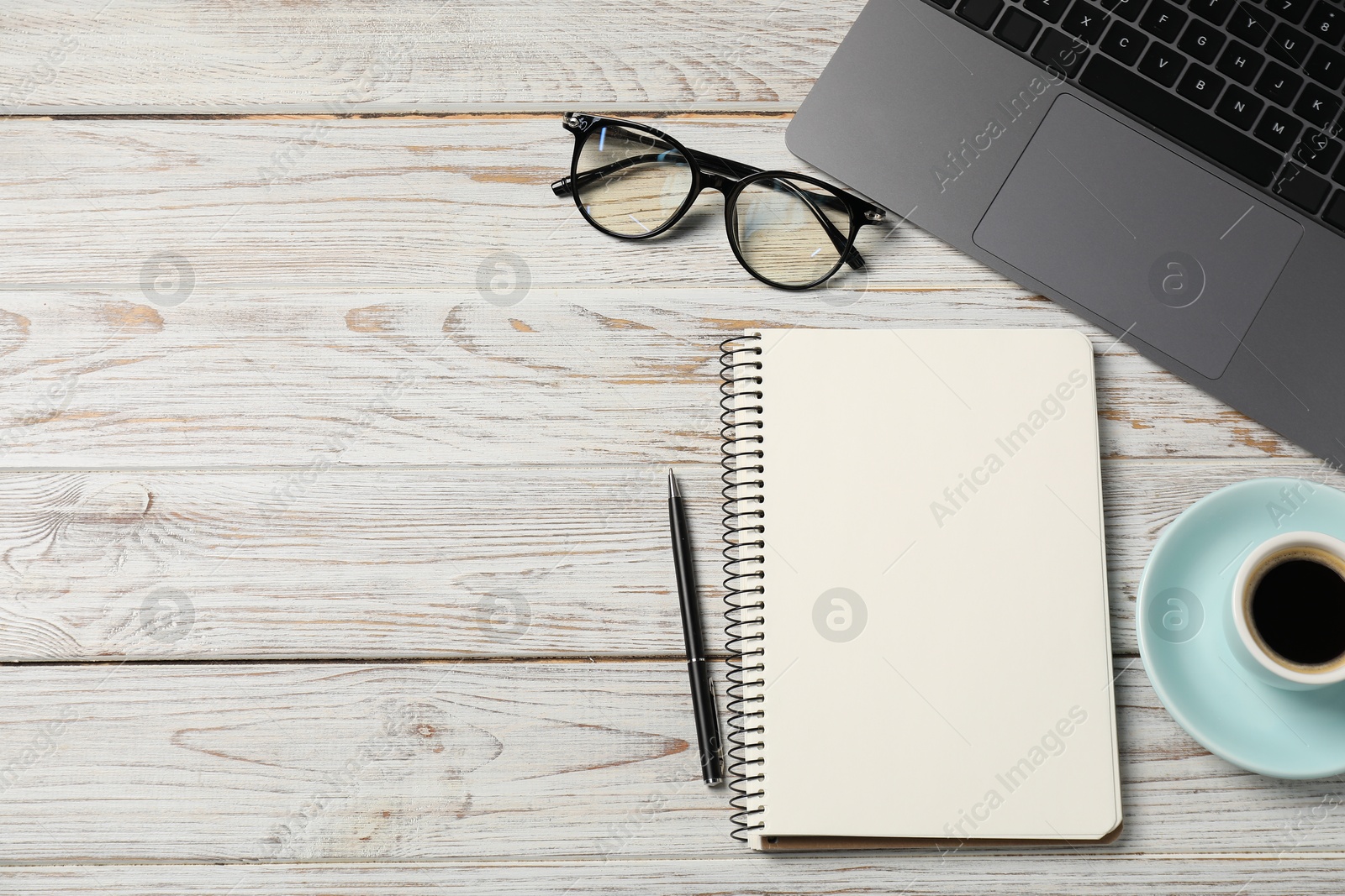 Photo of Notebook with pen, laptop, glasses and coffee on white wooden table, flat lay. Space for text