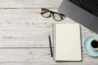 Photo of Notebook with pen, laptop, glasses and coffee on white wooden table, flat lay. Space for text