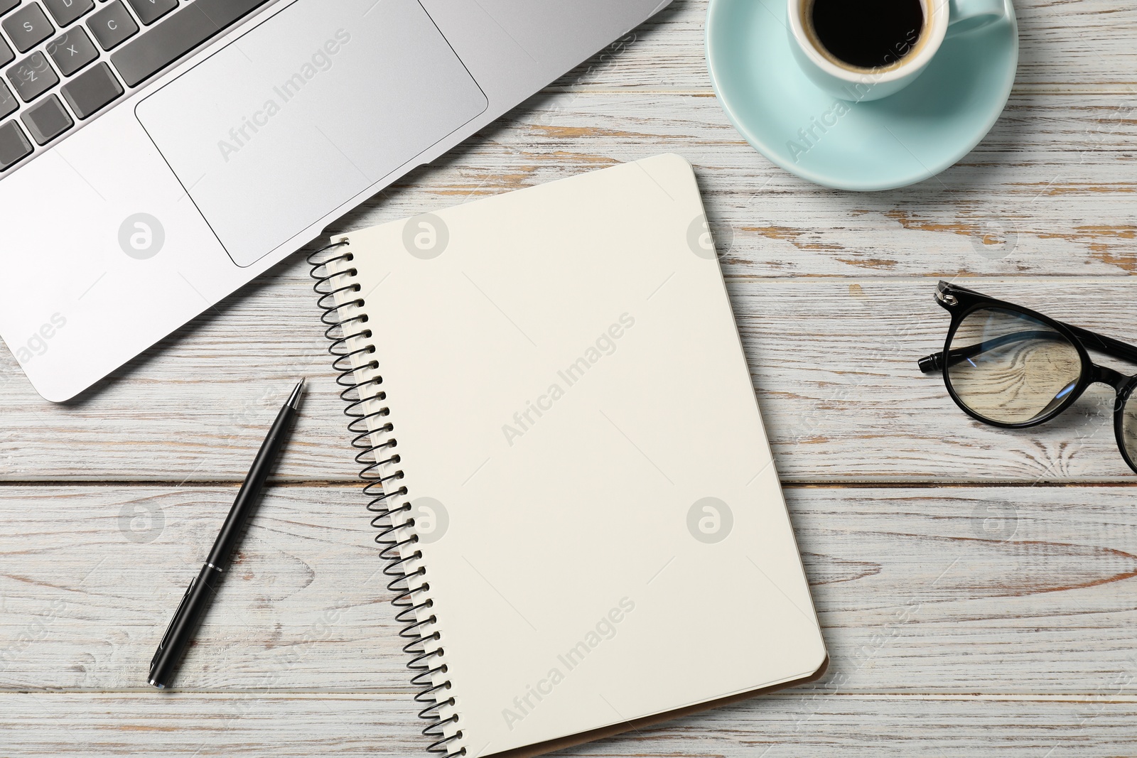 Notebook with pen, laptop, glasses and coffee on white wooden table, flat lay Photo of Notebook with pen, laptop, glasses and coffee on white wooden table, flat lay