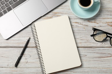 Photo of Notebook with pen, laptop, glasses and coffee on white wooden table, flat lay