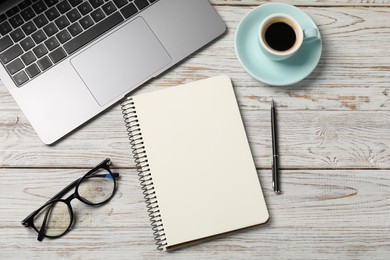 Photo of Notebook with pen, laptop, glasses and coffee on white wooden table, flat lay