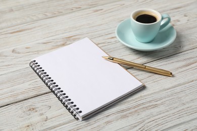 Photo of Notebook with pen and coffee on white wooden table, closeup