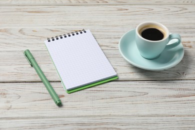 Photo of Notebook with pen and coffee on white wooden table