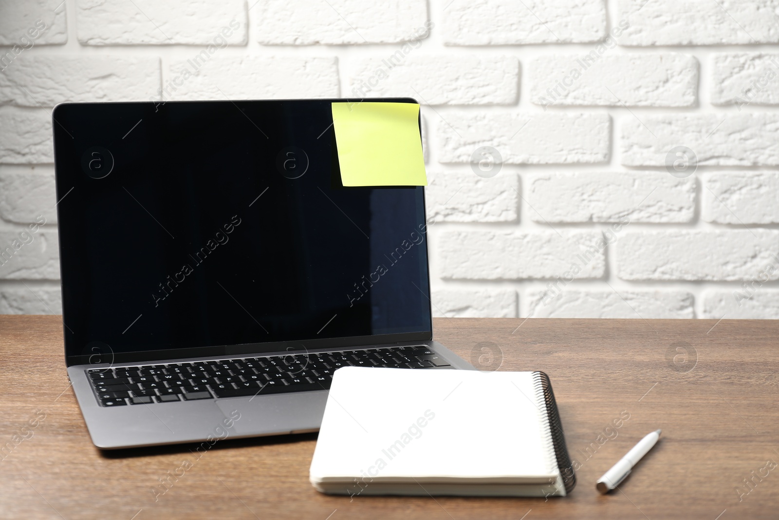 Laptop with sticky note, notebook and pen on wooden table. Space for text Photo of Laptop with sticky note, notebook and pen on wooden table. Space for text