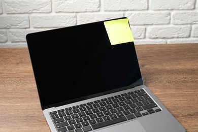Photo of Laptop with sticky note on wooden table