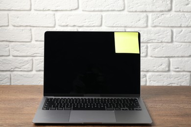 Photo of Laptop with sticky note on wooden table