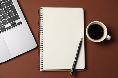 Photo of Notebook with pen, laptop and coffee on brown background, flat lay