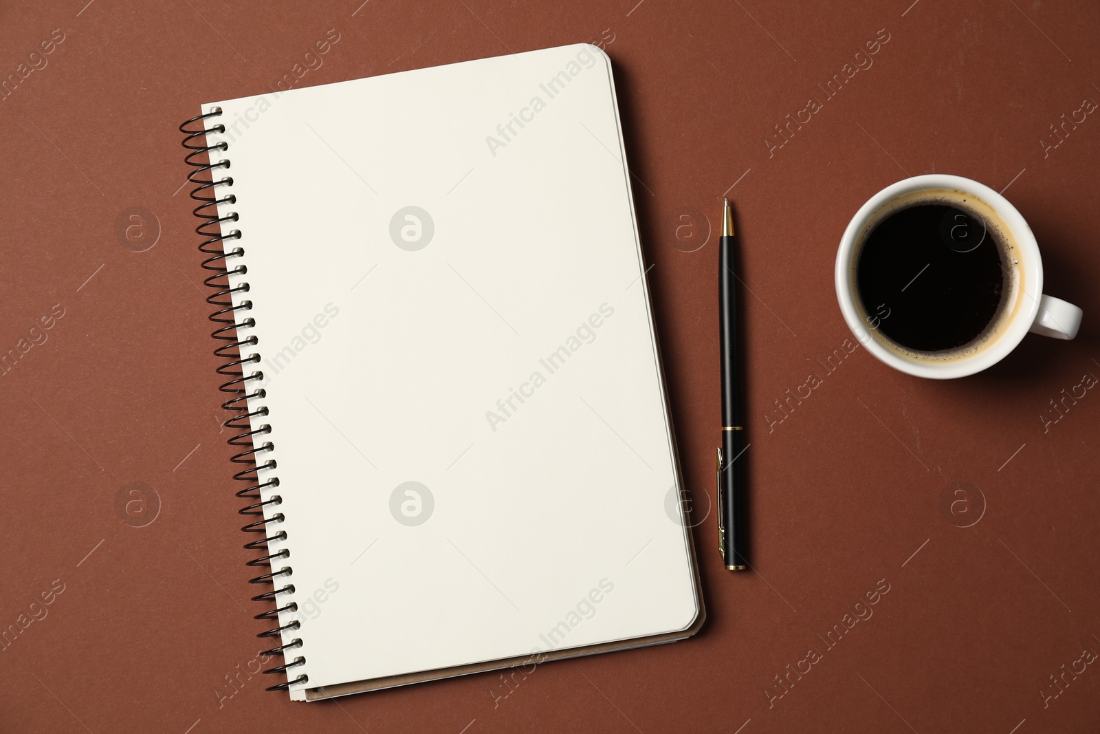 Photo of Notebook with pen and coffee on brown background, flat lay