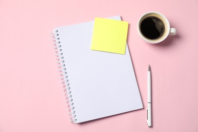 Photo of Notebook with sticky note, pen and coffee on pink background, top view