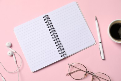 Photo of Notebook with pen, earphones, glasses and coffee on pink background, flat lay