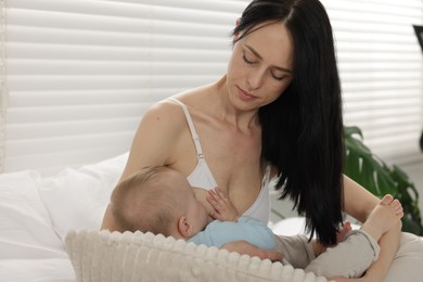 Photo of Mother breastfeeding her little baby on bed at home