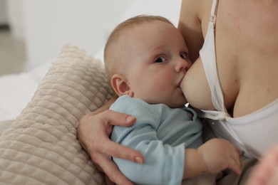 Photo of Mother breastfeeding her little baby indoors, closeup