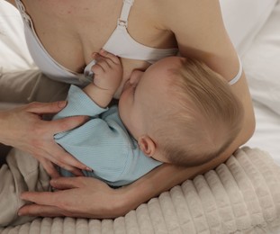 Photo of Mother breastfeeding her little baby indoors, closeup
