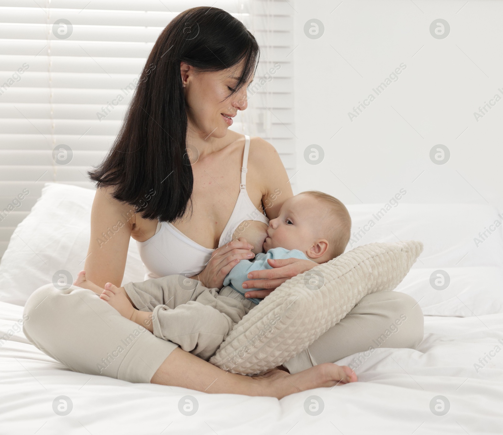 Smiling mother breastfeeding her little baby on bed at home Photo of Smiling mother breastfeeding her little baby on bed at home