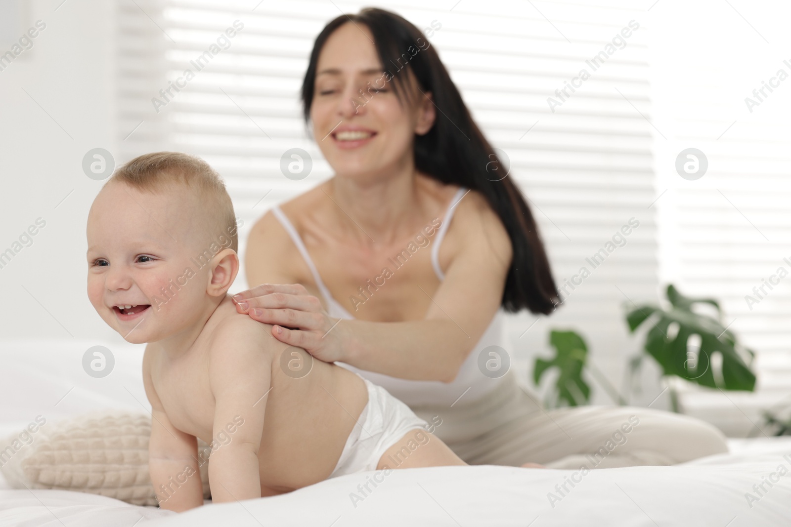 Smiling mother with her little baby on bed at home, selective focus Photo of Smiling mother with her little baby on bed at home, selective focus