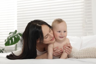 Photo of Smiling mother with her little baby on bed at home