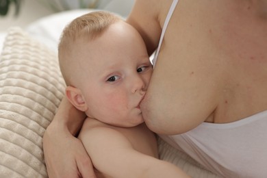 Photo of Mother breastfeeding her little baby indoors, closeup