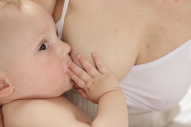 Photo of Mother breastfeeding her little baby indoors, closeup