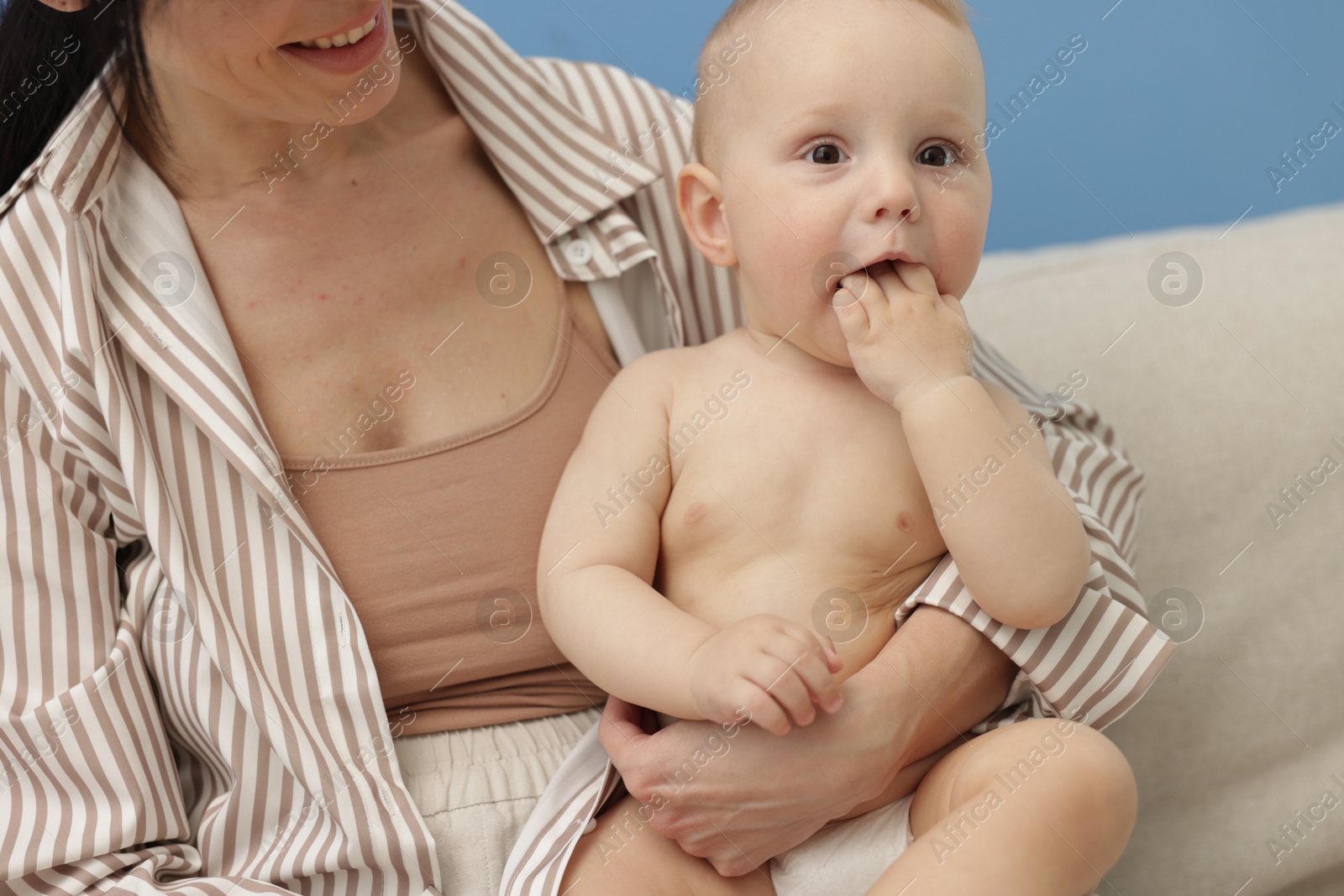 Smiling mother with her little baby on sofa indoors Photo of Smiling mother with her little baby on sofa indoors