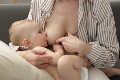 Photo of Mother breastfeeding her little baby on sofa indoors, closeup