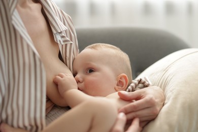 Photo of Mother breastfeeding her little baby indoors, closeup