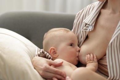 Photo of Mother breastfeeding her little baby indoors, closeup