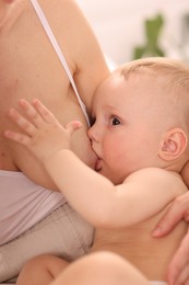 Photo of Mother breastfeeding her little baby indoors, closeup