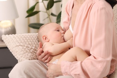 Photo of Mother breastfeeding her little baby indoors, closeup