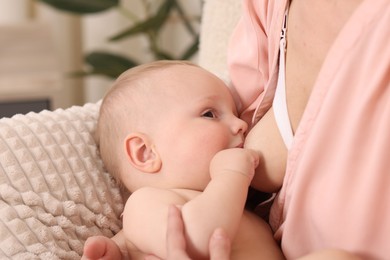 Photo of Mother breastfeeding her little baby indoors, closeup