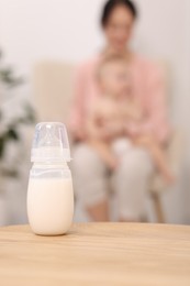 Photo of Mother with her little baby indoors, focus on bottle of milk