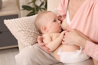Photo of Mother breastfeeding her little baby indoors, closeup