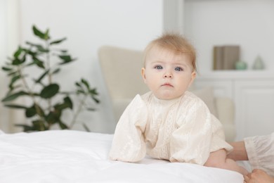 Photo of Cute little baby and mother on bed at home, closeup