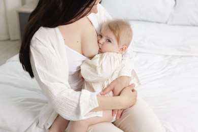 Photo of Mother breastfeeding her little baby on bed indoors, closeup
