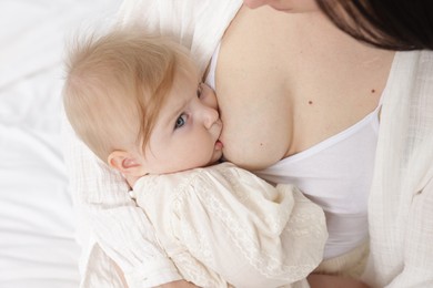 Photo of Mother breastfeeding her little baby on bed, closeup