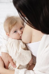Photo of Mother breastfeeding her little baby on bed, closeup