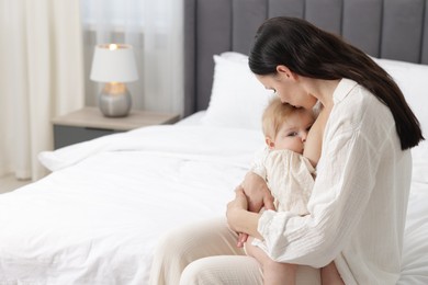 Photo of Mother breastfeeding her little baby on bed indoors. Space for text