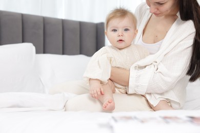 Photo of Mother with her little baby on bed indoors