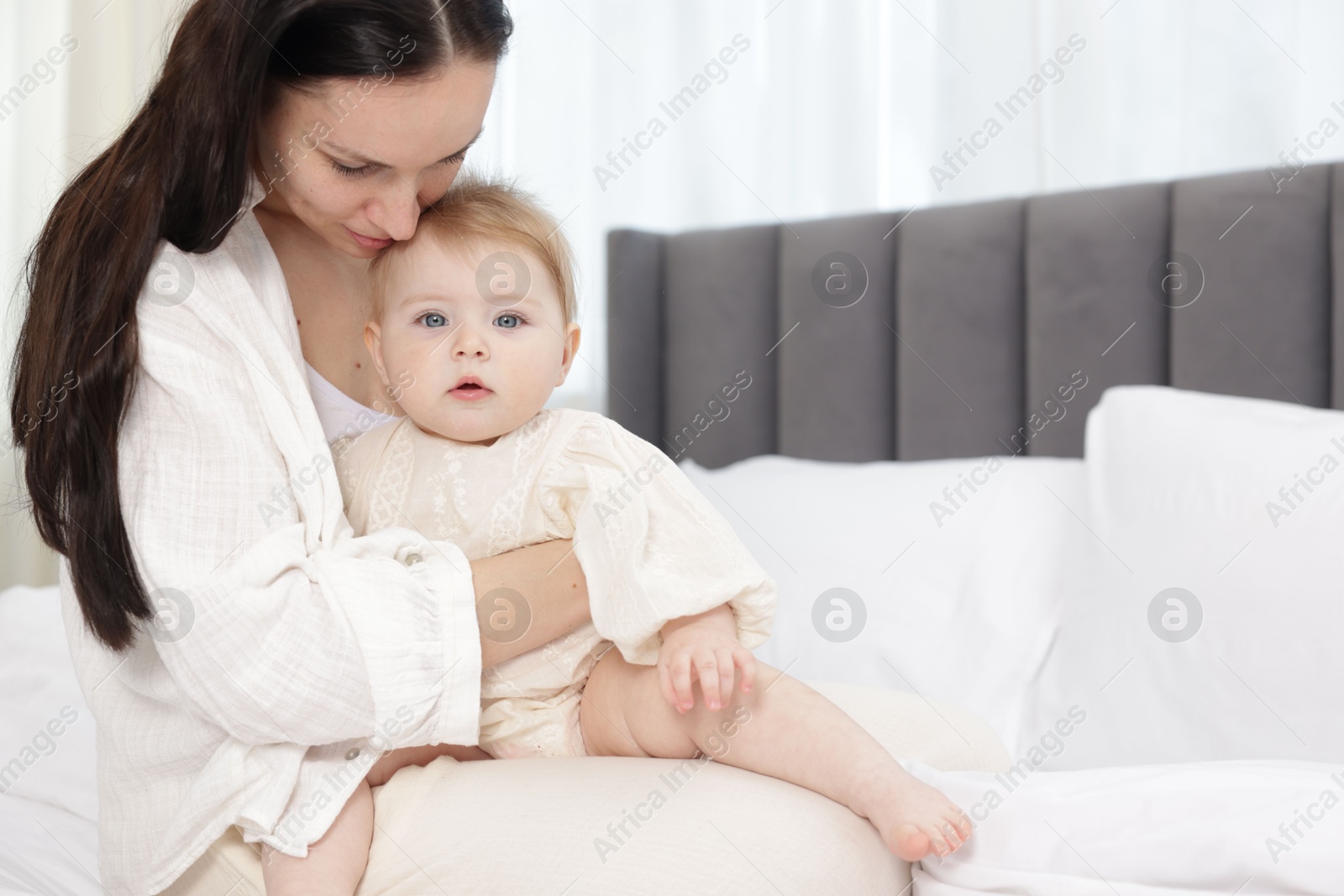 Mother with her little baby on bed indoors Photo of Mother with her little baby on bed indoors