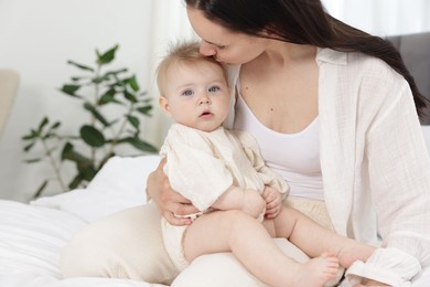 Photo of Mother kissing her little baby on bed at home