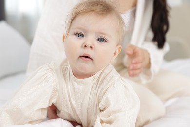 Photo of Cute little baby and mother on bed, selective focus