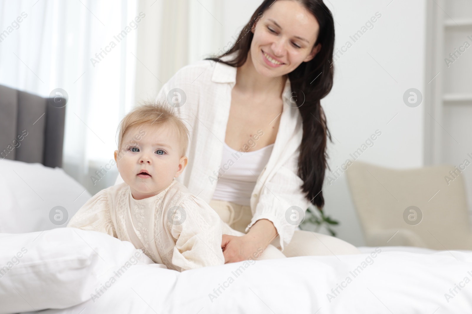 Smiling mother with her little baby on bed at home Photo of Smiling mother with her little baby on bed at home