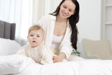 Photo of Smiling mother with her little baby on bed at home