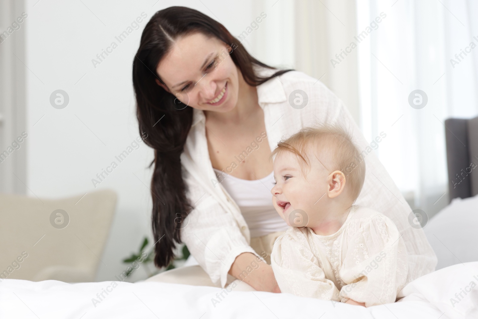 Smiling mother with her little baby on bed at home Photo of Smiling mother with her little baby on bed at home