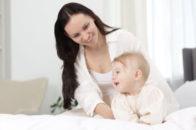 Photo of Smiling mother with her little baby on bed at home