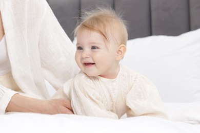 Photo of Cute little baby and mother on bed, closeup